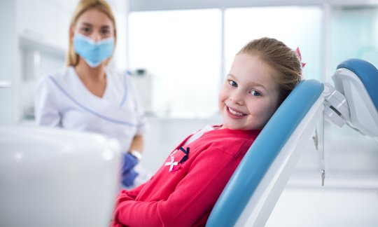 Pediatric dentist examining a child's teeth during a checkup covered by PPO dental insurance
