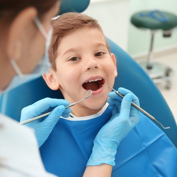 Dentist examining little boy's teeth in clinic