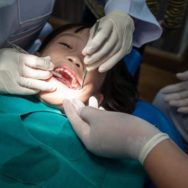 Asian girl met the dentist for routine dental checkup and consultant. Dental cleaning process.