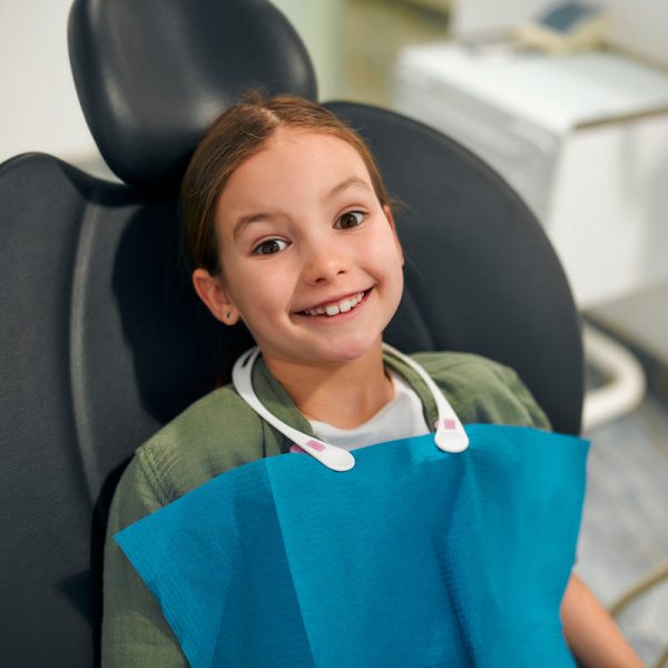 Child little girl sitting on a dental chair on examination by a pediatric dentist in a dental clinic. Dentistry and care of milk teeth.