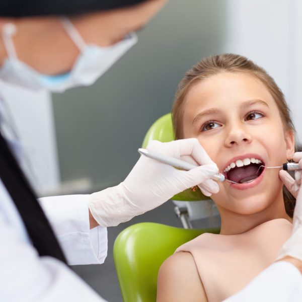 Teeth checkup at dentist's office. Dentist examining girls teeth in the dentists chair